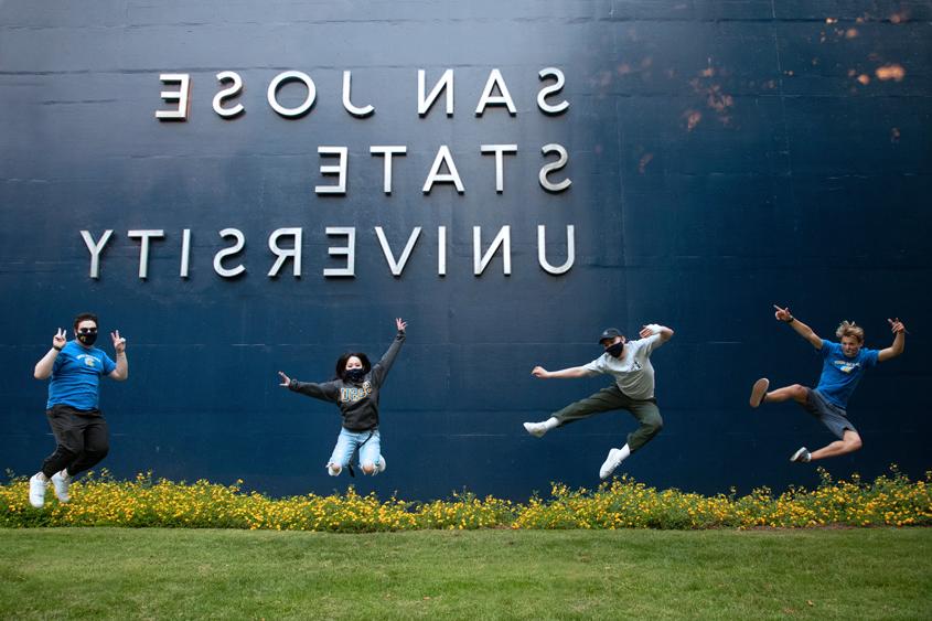 Students jumping up in the air in front of the 菠菜网lol正规平台 sign.